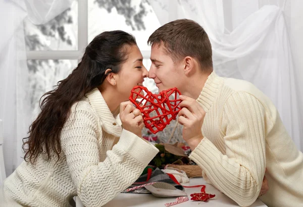 Jovem casal beijo e mostra um coração vermelho, pessoas felizes - conceito romântico e amor — Fotografia de Stock