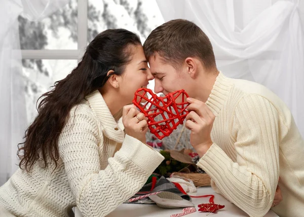 Jovem casal beijo e mostra um coração vermelho, pessoas felizes - conceito romântico e amor — Fotografia de Stock