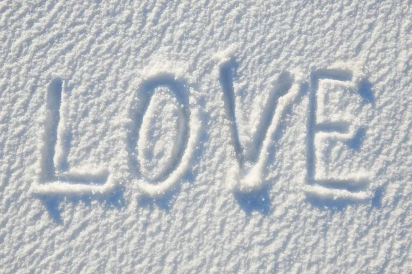 Love text written on snow for texture or background - winter holiday concept. Sunny day, bright light with shadows, flat lay, top view, clean and nobody — Stock Photo, Image