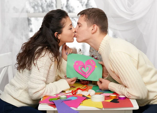 Romantica giovane coppia si siede a tavola e mostra origami cuore rosso, persone felici e concetto di amore — Foto Stock