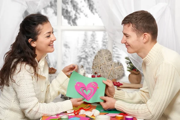 Romantische jong koppel zitten aan de tafel en shows origami rood hart, gelukkige mensen en begrip van de liefde — Stockfoto