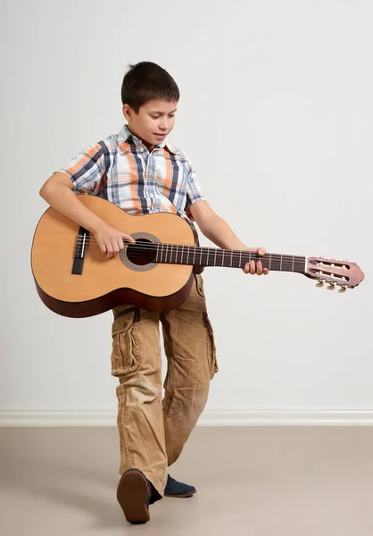 Boy está tocando a guitarra acústica em fundo branco — Fotografia de Stock