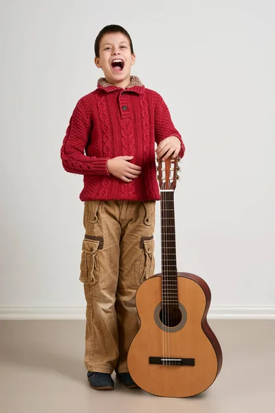 Niño divirtiéndose con la guitarra, haciendo música y cantando Imagen de stock