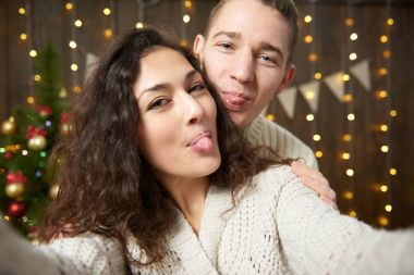 Mutlu çift selfie alarak ve Noel dekorasyonu eğleniyor. Koyu ahşap iç ışıkları ile. Romantik akşam ve sevgi kavramı. Yeni yıl tatili.
