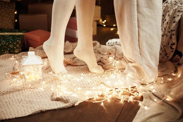 Fiatal pár, sötét fából készült belső fény, gyertya lantern lábak. Férfi és nő, átölelve. Újévi ünnep. Karácsonyi fények és a dekoráció. Fehérbe öltözött. Romantikus este. — Stock Fotó