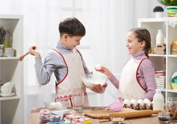 Girl and boy cooking in home kitchen. The boy breaks the egg. Healthy food concept — Stock Photo, Image