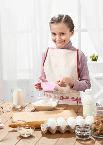 Girl cooking in home kitchen, sifts flour through a sieve, healthy food concept — Stock Photo, Image