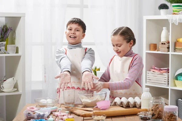 Girl and boy cooking in home kitchen. Children show hands with flour. — Stock Photo, Image