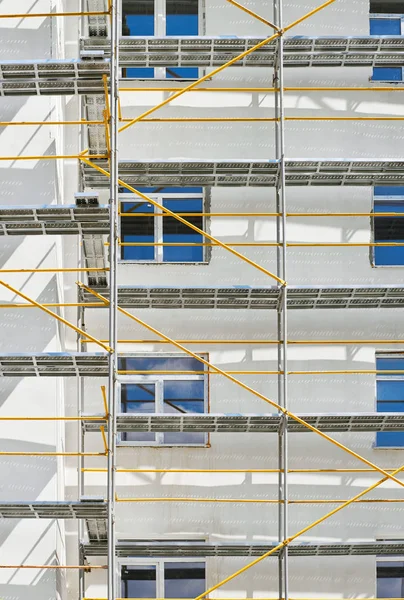 Scaffolding near a new house under construction, white wall and window, yellow pipe — Stock Photo, Image