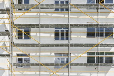 İnşaat, beyaz duvar ve pencere, sarı boru altında yeni bir ev yakınındaki Yapı iskelesi