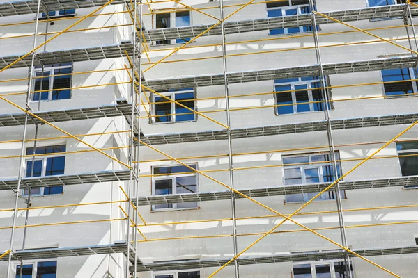 Échafaudage près d'une maison neuve en construction, mur blanc et fenêtre, tuyau jaune — Photo