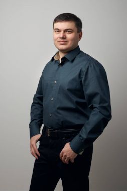gri arka plan üzerinde gömlek ve siyah pantolon giymiş adam portresi