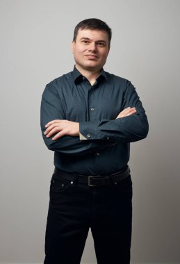 gri arka plan üzerinde gömlek ve siyah pantolon giymiş adam portresi
