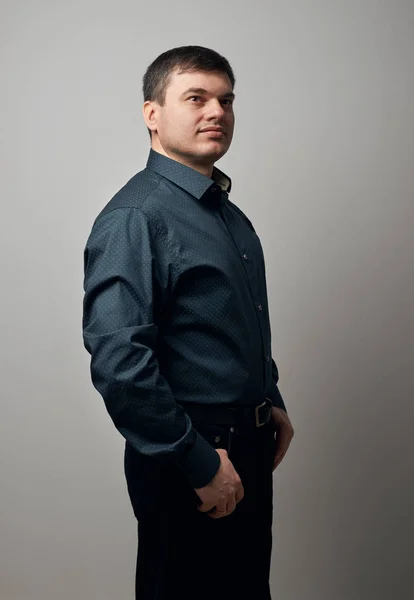 Männerporträt gekleidet in Hemd und schwarzer Hose vor grauem Hintergrund — Stockfoto
