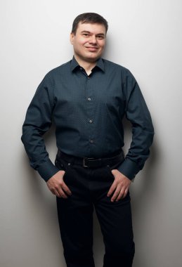 gri arka plan üzerinde koyu gömlek ve siyah pantolon giymiş adam portresi