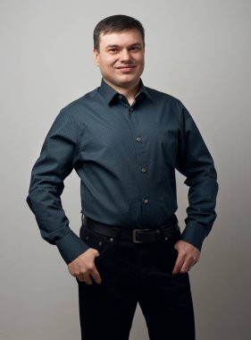 gri arka plan üzerinde koyu gömlek ve siyah pantolon giymiş adam portresi