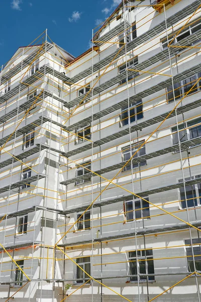 Σκαλωσιές κοντά σε ένα νέο σπίτι, το κτήριο εξωτερικά, βιομηχανία κατασκευής και επισκευής, λευκό τοίχο και παράθυρο, κίτρινο σωλήνα — Φωτογραφία Αρχείου
