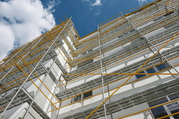 Échafaudage près d'une maison neuve, bâtiment extérieur, construction et réparation, mur blanc et fenêtre, tuyau jaune — Photo