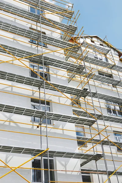 Gerüste in der Nähe eines neuen Hauses, Gebäude außen, Bau- und Reparaturindustrie, weiße Wand und Fenster, gelbes Rohr — Stockfoto