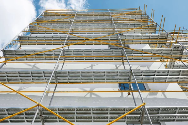 Échafaudage près d'une maison neuve, bâtiment extérieur, construction et réparation, mur blanc et fenêtre, tuyau jaune — Photo