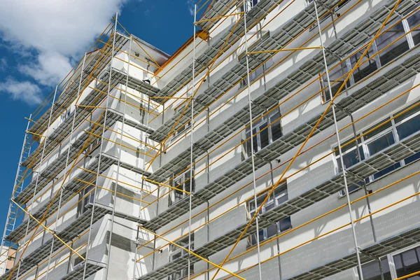 Andaimes perto de uma nova casa, construção exterior, construção e indústria de reparação, parede branca e janela, tubo amarelo — Fotografia de Stock