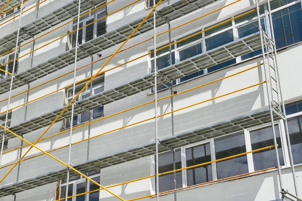 Gerüste in der Nähe eines neuen Hauses, Gebäude außen, Bau- und Reparaturindustrie, weiße Wand und Fenster, gelbes Rohr — Stockfoto