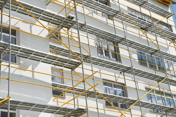 Steigers in de buurt van een nieuw huis, gebouw, exterieur, bouw-en scheepsreparatiesector, witte muur en venster, gele pijp — Stockfoto