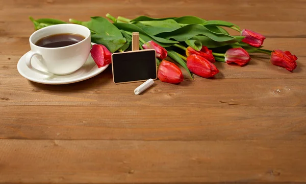 Tulipani sono su tavole di legno, tazza di caffè con piccola lavagna, concetto di saluto in stile retrò — Foto Stock