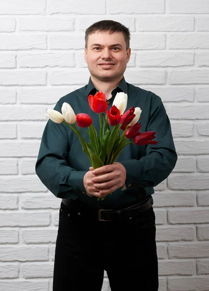 Mannen med blommor på vit tegel vägg bakgrund, holiday och hälsningar koncept — Stockfoto