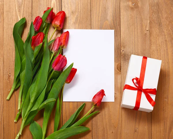 Tulipani sono su tavole di legno, foglio di carta bianca e regalo, concetto di saluto — Foto Stock