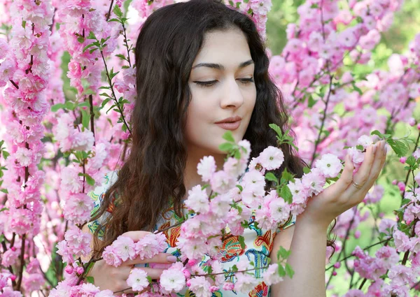 Portrét mladé dívky na pozadí růžové květy, tvář zblízka — Stock fotografie