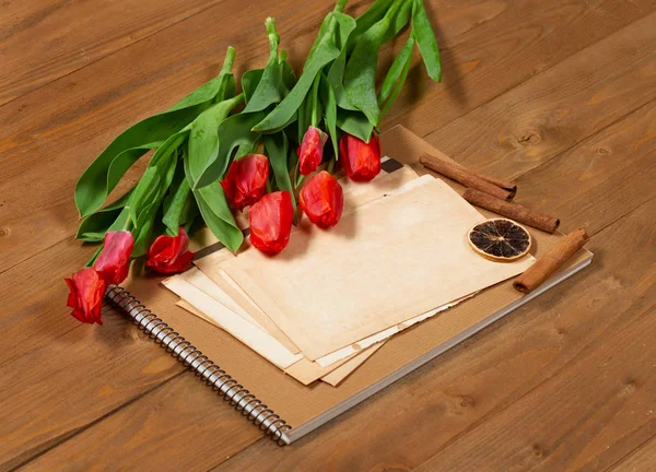 Tulipány jsou na dřevěných desek, staré listy prázdného papíru pro text, pozdrav koncept v retro stylu — Stock fotografie