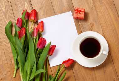 Lale ahşap kurullarında, fincan kahve, boş kağıt sayfası ve hediye, kavram tebrik vardır