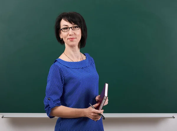 Kvinna lärare poserar vid krita styrelsen, lärande koncept, grön bakgrund, Studio skott — Stockfoto