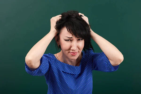 Жінка вчителька в стресі позує крейдяною дошкою, сльози її волосся, концепція навчання, зелений фон, студійний знімок — стокове фото