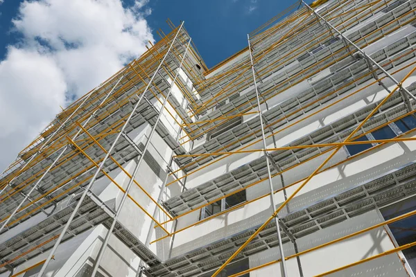 Échafaudage près d'une maison neuve, bâtiment extérieur, construction et réparation, mur blanc et fenêtre, tuyau jaune — Photo