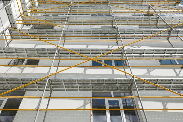 Andamios cerca de una nueva casa, edificio exterior, industria de la construcción y reparación, pared blanca y ventana, tubería amarilla —  Fotos de Stock