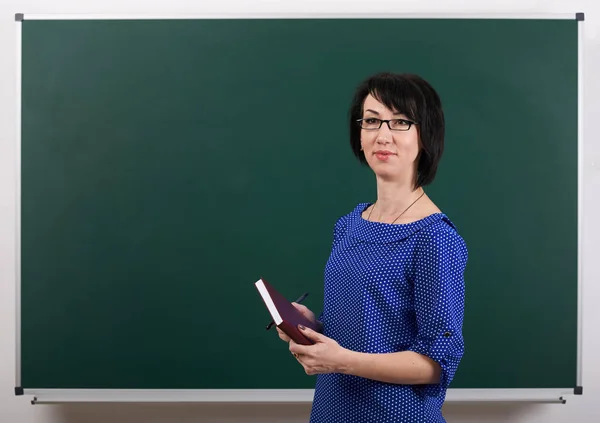 Жінка-вчитель позує на крейдяній дошці, концепція навчання, зелений фон, студійний знімок — стокове фото