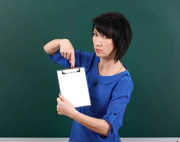 Mujer estudiante mostrar hoja de papel en blanco cerca de pizarra Junta, concepto de educación, fondo verde, plano de estudio — Foto de Stock