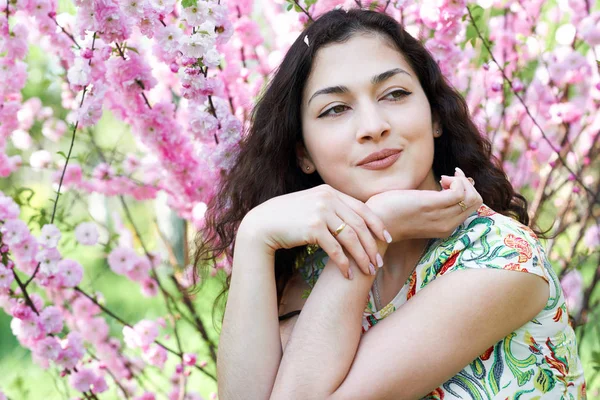 Portrait of young beautiful girl on pink flowers background, face close up — Stock Photo, Image