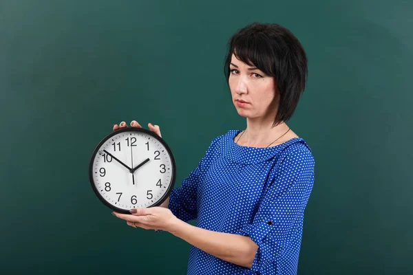 Mujer con gran reloj posando por pizarra, tiempo y concepto de educación, fondo verde, plano de estudio — Foto de Stock