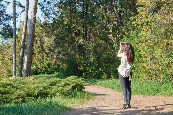 Chica con cámara tomando fotos de la naturaleza en primavera, hermoso bosque y árboles en un día soleado —  Fotos de Stock