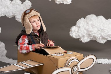karton kutu ve bir pilot olma hayalleri bulutlar Pamuk yün gri bir arka plan üzerine yapılmış bir uçak çocuk oynar