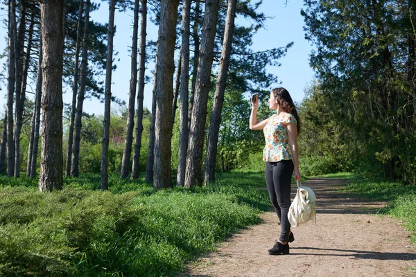 Chica con cámara tomando fotos de la naturaleza en primavera, hermoso bosque y árboles en un día soleado —  Fotos de Stock