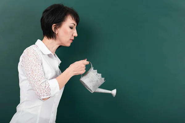 Una mujer con una regadera en las tablas de fondo, espacio vacío para su imagen — Foto de Stock