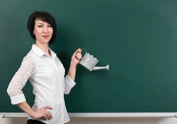 A woman with a watering can on the background boards, empty space for your picture Royalty Free Stock Photos