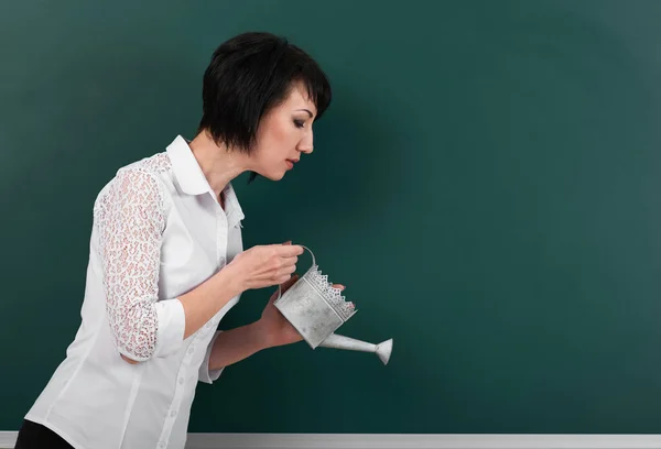 Eine Frau mit einer Gießkanne auf den Hintergrundbrettern, leerer Raum für Ihr Bild — Stockfoto