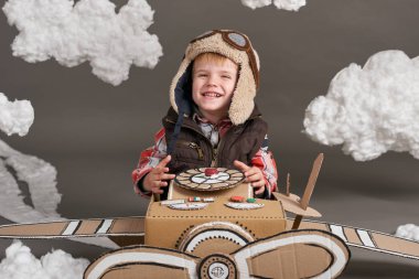 karton kutu ve bir pilot olma hayalleri bulutlar Pamuk yün gri bir arka plan üzerine yapılmış bir uçak çocuk oynar