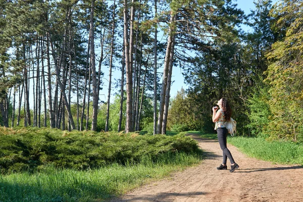 Chica con cámara tomando fotos de la naturaleza en primavera, hermoso bosque y árboles en un día soleado —  Fotos de Stock