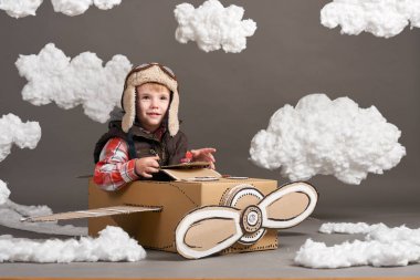 karton kutu ve bir pilot olma hayalleri bulutlar Pamuk yün gri bir arka plan üzerine yapılmış bir uçak çocuk oynar